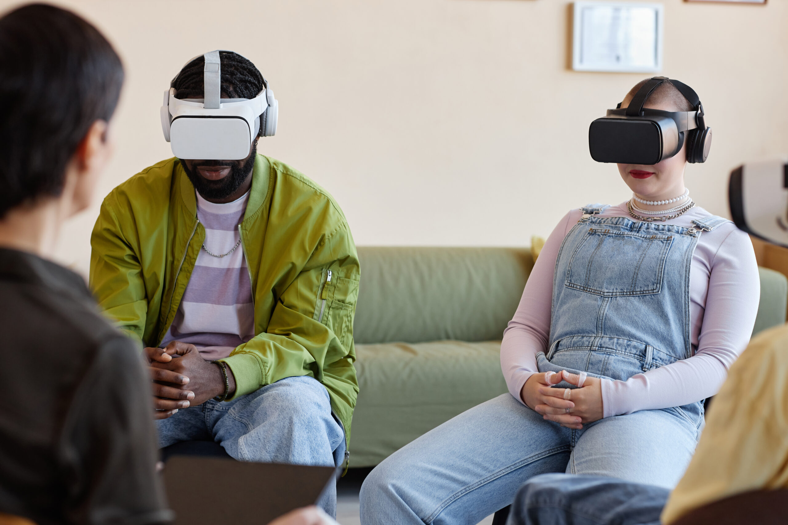 Young people in VR glasses talking to psychologist during meeting in office